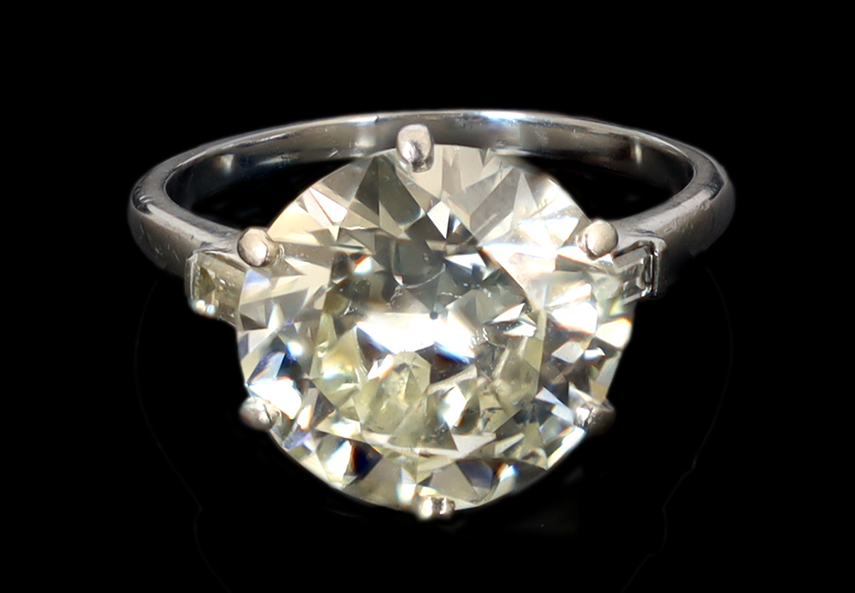 A platinum and single stone diamond set ring, with baguette cut diamond set shoulders